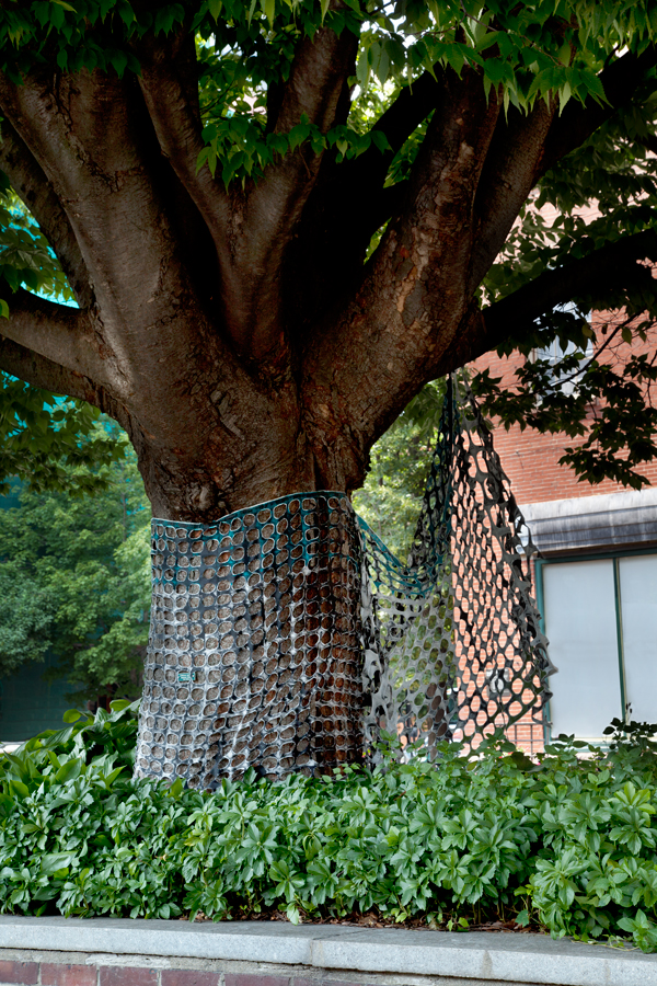 Wrapped tree behind Fence/Curtain 2.0, 120 long x 48" high, Temporary public art installation in Boston, MA, USA, 100% cotton, paint, thread, Monoprinted, handstamped, handpainted, stitched, cut stiffened fabric, Photo credit: Will Howcroft.