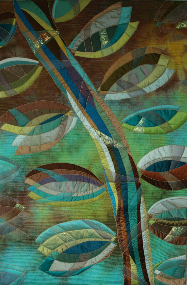 Ocean Blue (102 x 152 cm), Materials: cotton, silk, organza, angelina. Leaves of silk and organza, with a stem of silk and organza are appliqued on a cotton surface. The leaves are drawn freehand. Angelina is being used sparingly to add some glitter. The surface is intensively quilted in order to have the leaves to come more forward. The fluid lines of the leaves have been followed. On the sides you can see parts of leaves made out of organza. By not using silk, they are less conspicuous.