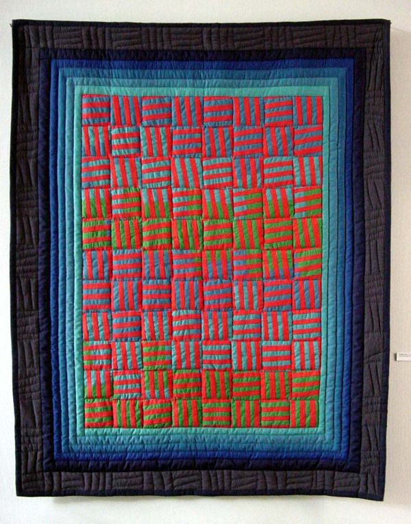 Bending Red, 1995, 44" x 55", textile hanging, machine-pieced and hand quilted cottons and poly-cottons. This work is a colour study in fabric exploring the possibility of altering the perception of one red by manipulating the adjacent colours. Photo: Judith Tinkl.