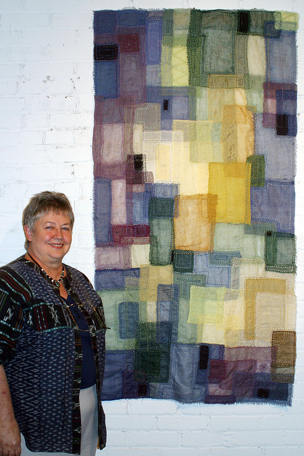 Facade XXII, with artist, 33 x 65 created with scrim raw edged appliqué hand stitched to a silk organza backing. Edges are also raw edged. Photo: Suzanne Rothwell