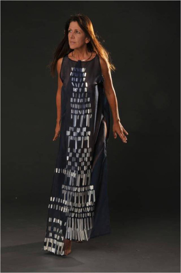 AGUA AL PUENTE (WATER FOR THE BRIDGE) is about abundance, flood, inundation, deluge, the river flow, tidal overflow, rain, tears, Aquarius, and Temperance: water in exaltation, unrestrained emotions. But when there is a riverbed, there is also the aquatic desire for a bridge.
«Water to the Bridge», a transparent blue tunic embroided with aluminum scales, represents the river, flood, deluge, mermaid, Aquarius, the Arcane called Temperance, and is the costume for an action in which I walk, with a jar, pouring water from my home to one of the few historic colonial bridges that remain in the city, over the now dried Quebrada Anauco.
Materials: man-made fabric; recycled aluminum; colored glass beads; ribbon. Hand sewn.
Photo: Maurizio Donelli. Model: Corina Fortoul.