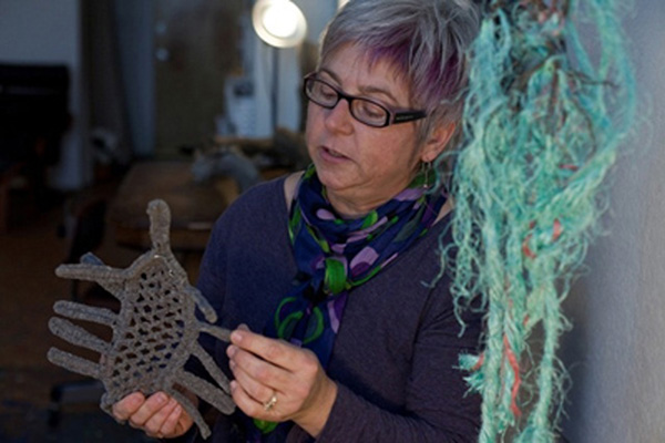 Artist in studio I -  Artist holding samples of studies of irish crochet to be used for a large sculpture. Photo by Melody Komyerov.