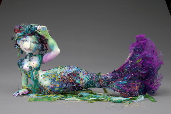 Moana, 12" H, undyed cotton, hand dyed cottons, silk, lace, netting, chiffon, wire, beads, old jewelry, hand dyed mohair, fabric paints, pencil crayon.
Moana won Best of Show at the 2005 Canadian Doll Artists Association Annual Conference. She was the very first mermaid I made and now I can't stop! The base of the figure was created from stitched layers of cottons, silks, chiffon, netting, and lace with tons of hand beading added at the end. The hair was needle felted onto her head after I added light washes of fabric paints to her face and arms.