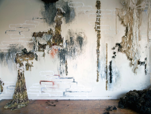 She Speaks Softly, 2010, 10’H x 18’W, alpaca wool, chicken wire, lace, upholstery fabric, plaster, spackle, charcoal, human hair, pastel, gesso, rubber latex. Technique: Layering materials on top of wall and then dismantling them. Photo: Mary Grisey. 