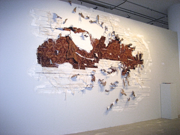 Excavated Memories, 2008, 9’H x 10’W, plaster, upholstery fabric, cardboard, paint, coffee, cheesecloth, spackle. Technique: Layering materials on top of the gallery wall, then dismantling them. Photo: Mary Grisey. 
