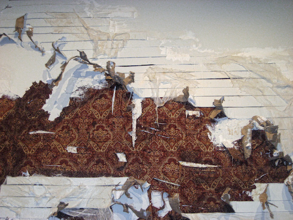 Excavated Memories, 2008, 9’H x 10’W, plaster, upholstery fabric, cardboard, paint, coffee, cheesecloth, spackle. Technique: Layering materials on top of the gallery wall, then dismantling them. Photo: Mary Grisey. 