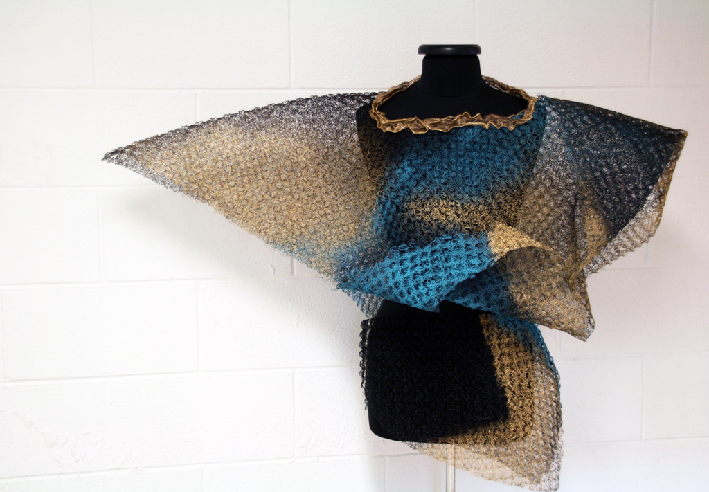 Folded Blue, 2015, 108H x 52W x 40D cm, plastic mesh salvaged from roofing industry, salvaged ribbon, aerosol paints, joined with cable ties.  Technique: Folding, cutting, stenciling.  