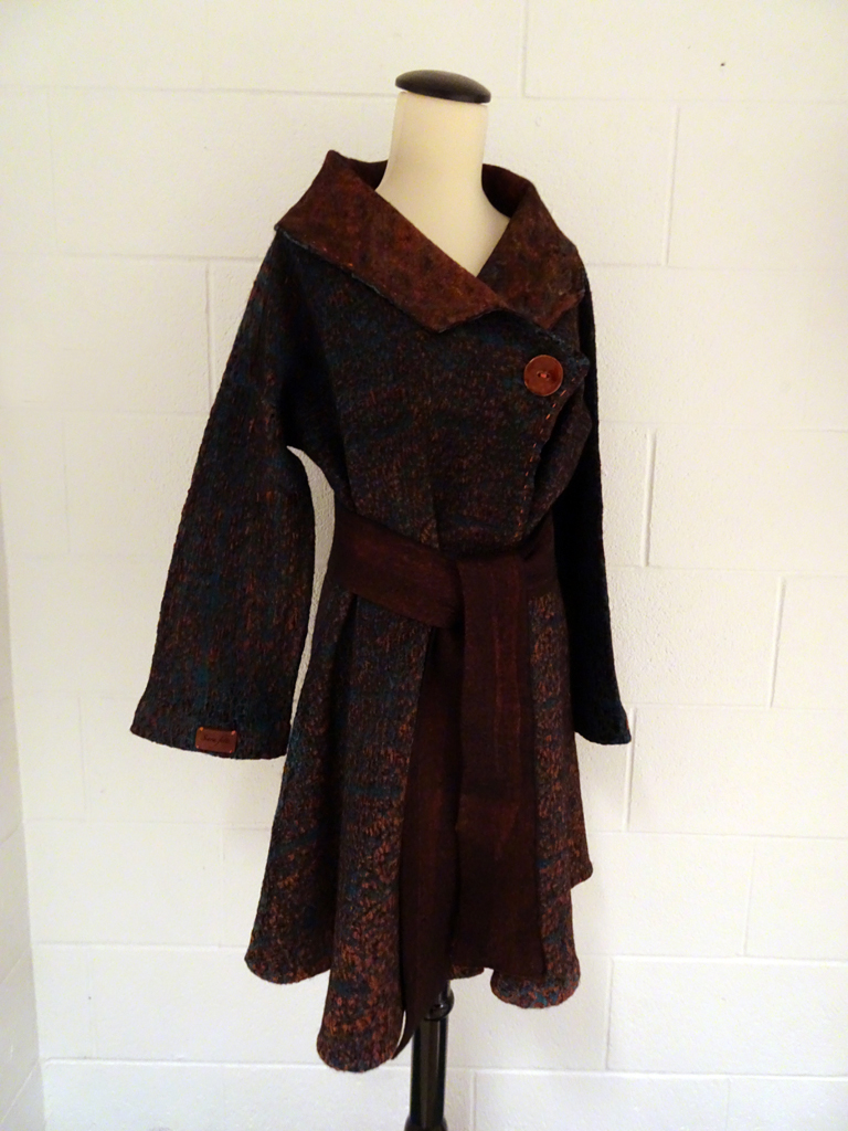 Vinitha Sara John: Velvet Vision swing coat, October 2017, Size 8.
This seamless reversible coat is made from superfine merino wool and silk velvet using the nuno felting technique. The collar is felted with silk fibers and the edges have been hand stitched with copper silk thread. The coat is black on the inside. It can be worn with or without the sash.