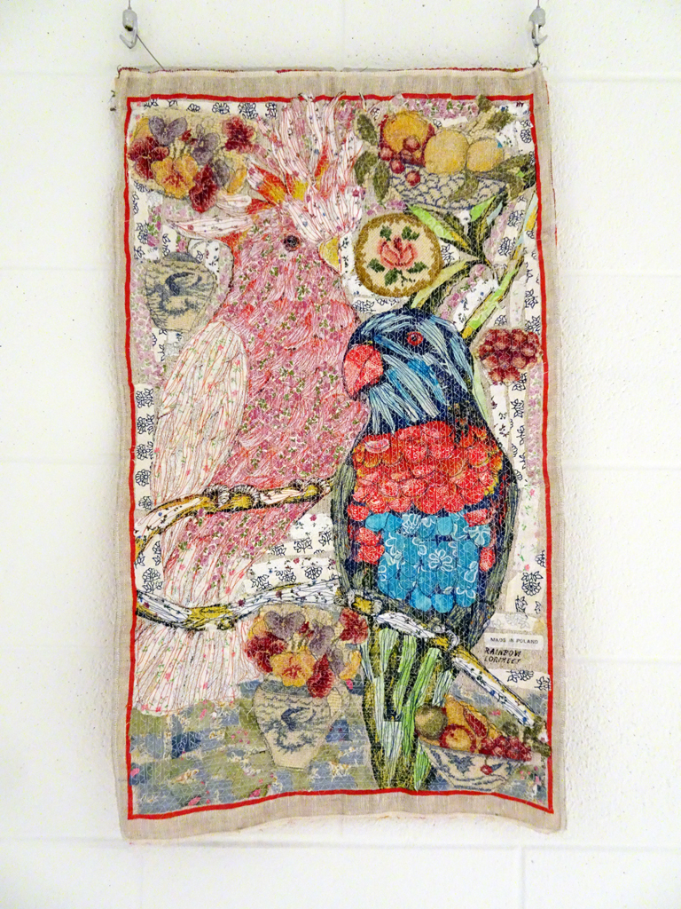 Judy Martin: Rainbow Lorikeet, 2017, 90 x 55 cm x .3 cm, linen tea towel, vintage needlepoint and petitpoint pieces, cotton, silk and linen scraps Technique: textile collage using hand and machine stitching.