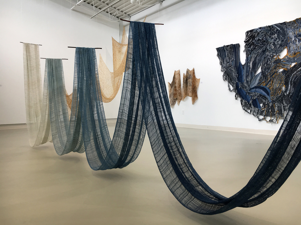Anna Heywood-Jones: Trace, 2017. 245 H x 70 W x 600 D. 
Materials: warp (wool, rayon and linen), weft (silk), indigo dye and wood. Technique: handwoven plainweave, incrementally hand-dyed with indigo. 
