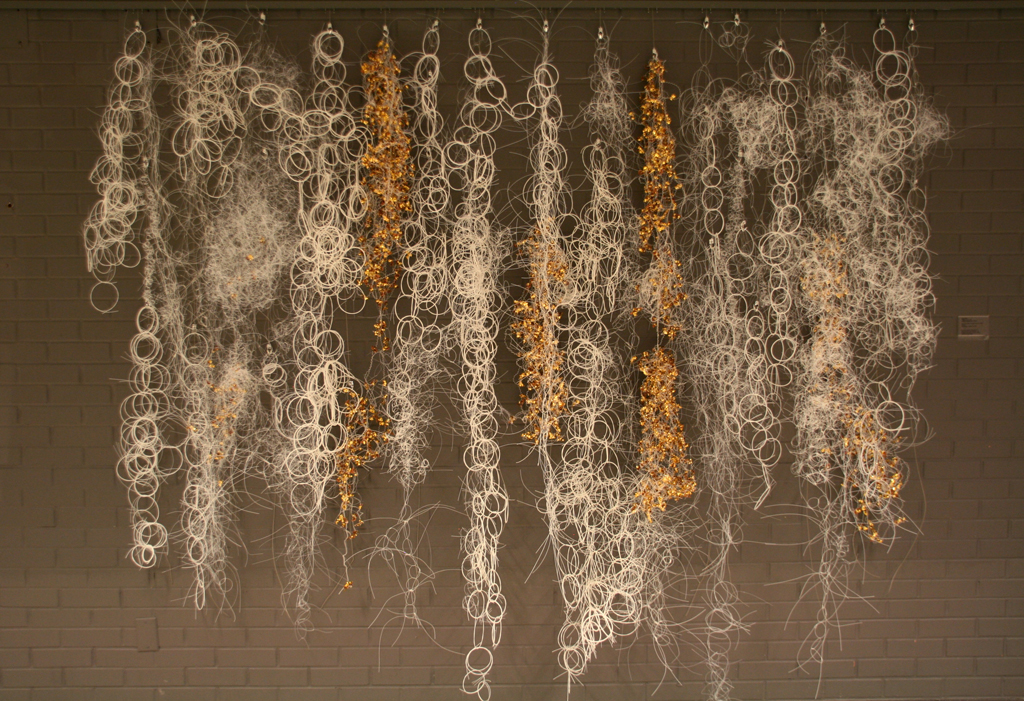 Yugen (A Mysterious Grace), 2016, 10W x 11H x 1D feet, nylon and metal salvaged from the zipper industry, Technique: knotting and wrapping to embed metal elements.  Installed on wall.