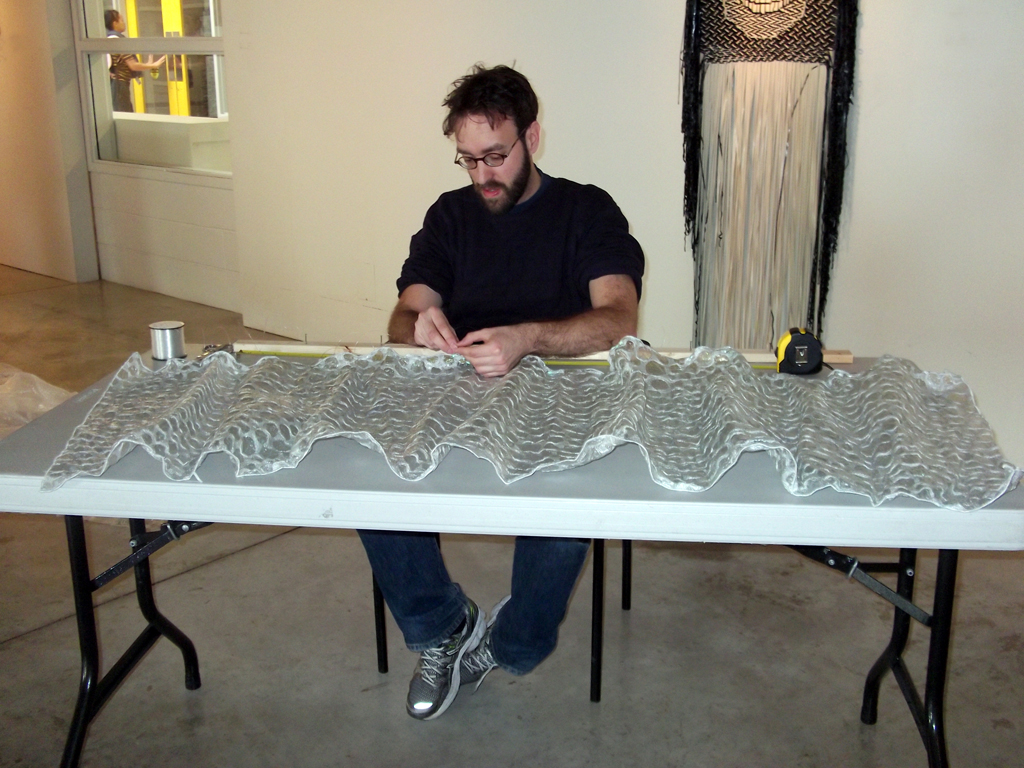 Curator Gareth Bate preparing artwork of Anna Hergert for installation.