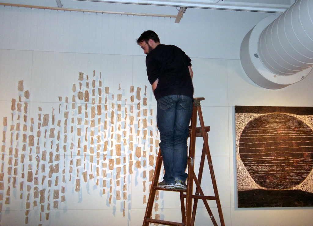 Curator Gareth Bate installing the artwork of Megan Bostic.