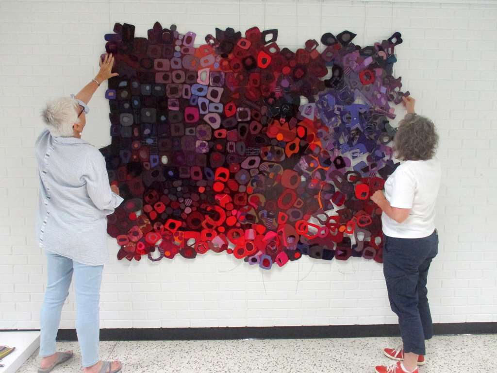 Festival installers Chris and Heidi, installing work in the Covid Forever exhibition, World of Threads Festival 2023-24.