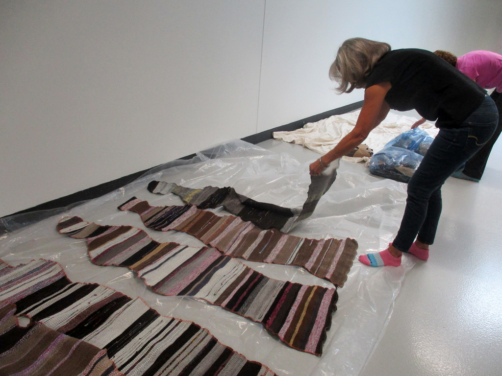 Artist: Carolyn Carson laying out The Ovine Conspiracy installation, World of Threads Festival 2023-24.