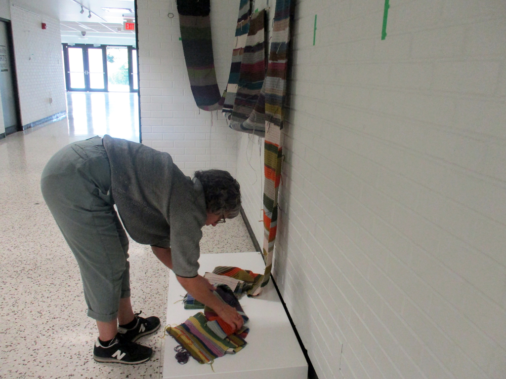 Michele Guevara installing her work in the Covid Forever exhibition, World of Threads Festival 2023-24.