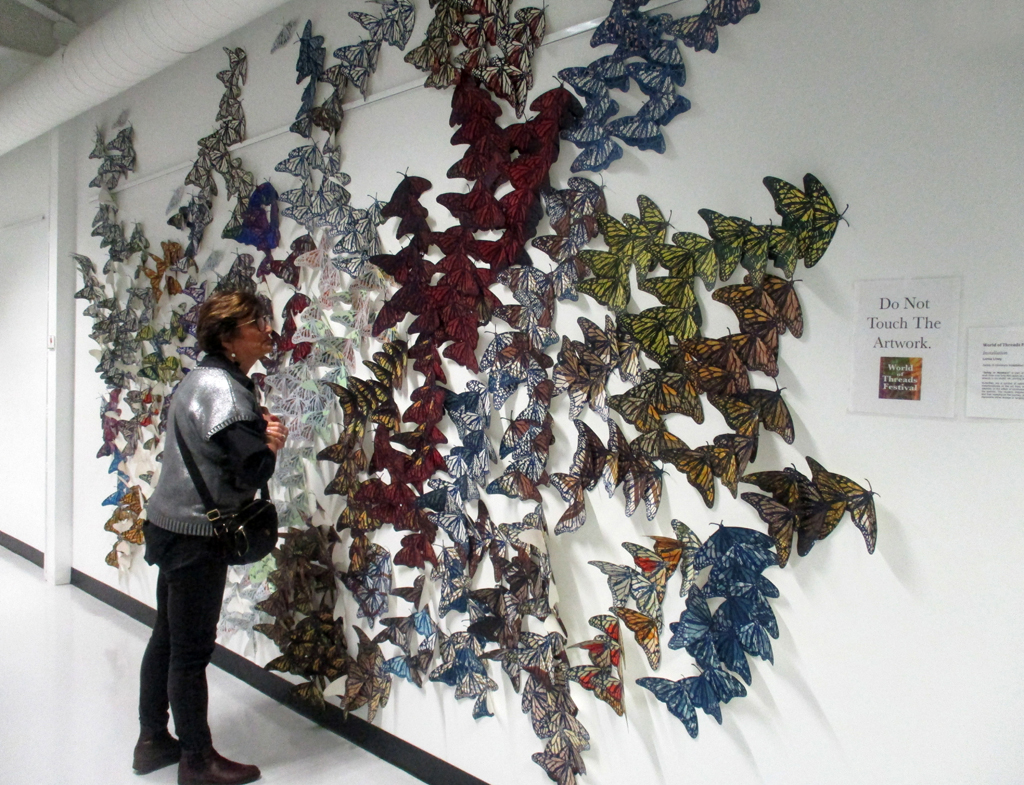 A visitors looking at the Safety in Numbers installation, World of Threads Festival 2023-24.