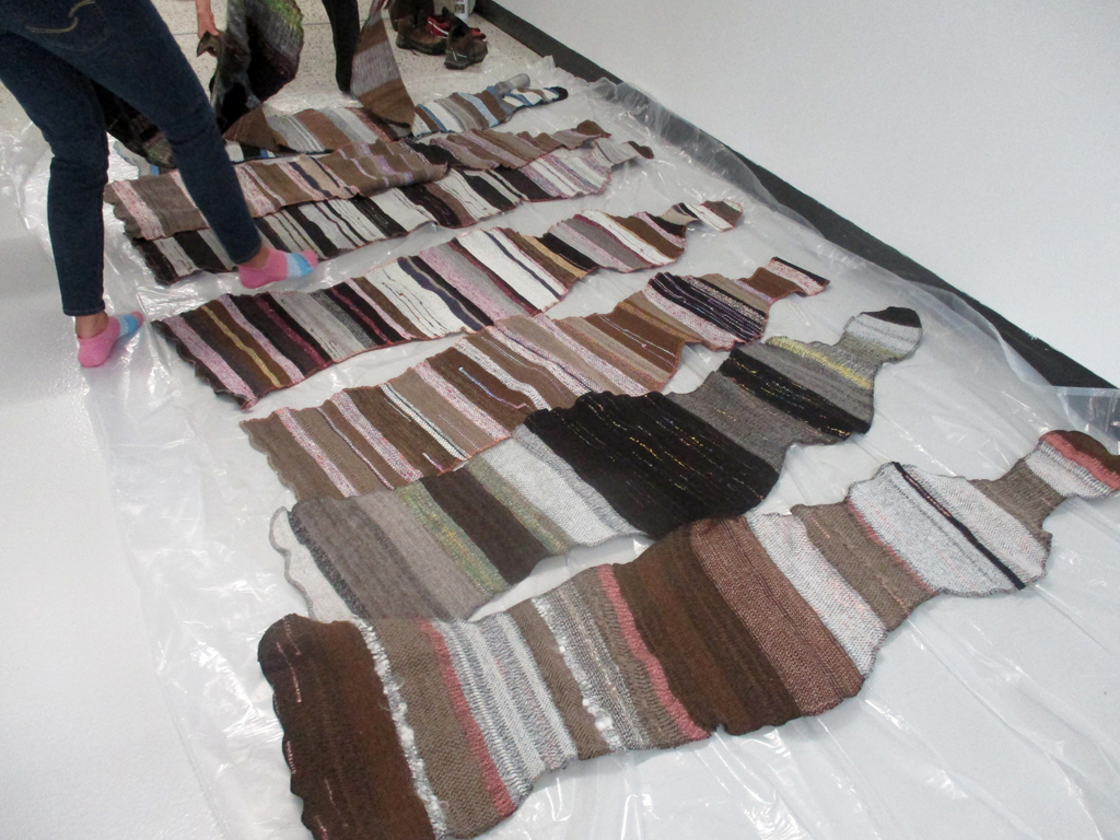 Artist: Carolyn Carson laying out The Ovine Conspiracy installation, World of Threads Festival 2023-24.