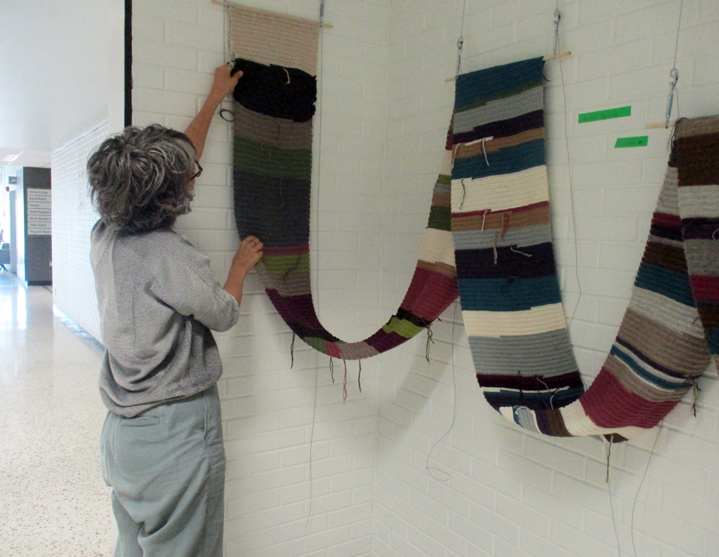 Michele Guevara installing her work in the Covid Forever exhibition, World of Threads Festival 2023-24.