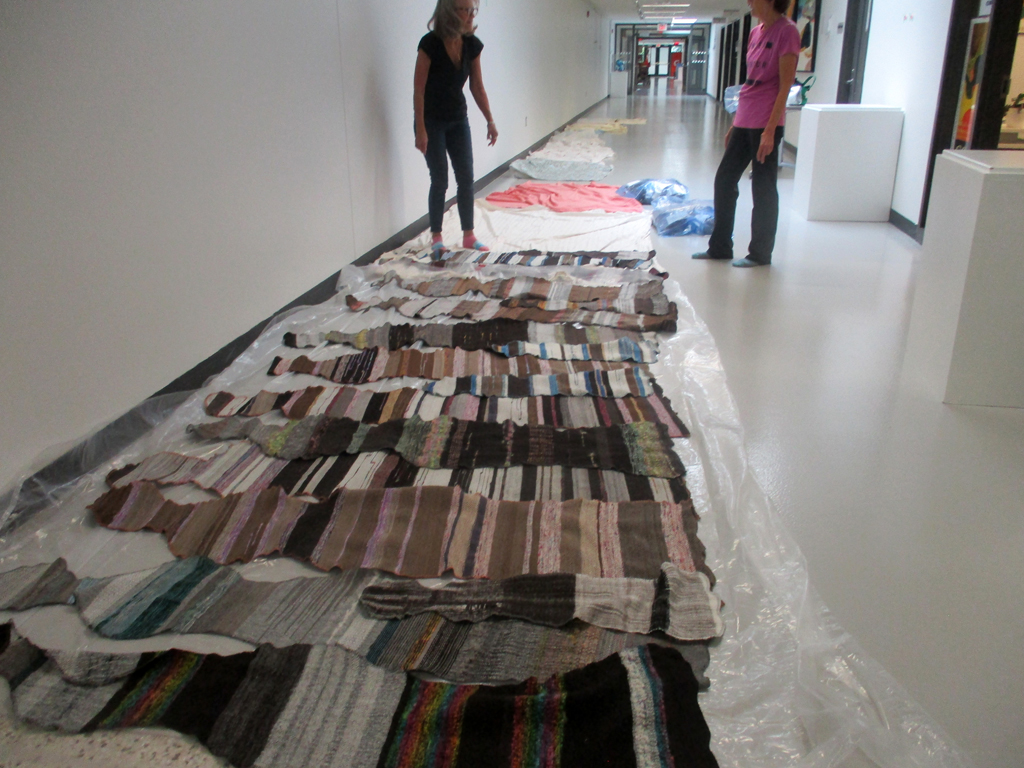 Artist: Carolyn Carson and Festival Installer: Margaret, laying out The Ovine Conspiracy installation, World of Threads Festival 2023-24.