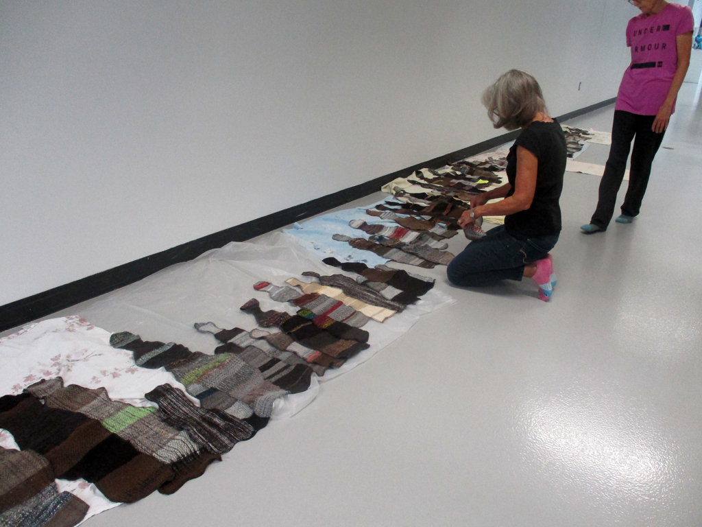 Artist: Carolyn Carson and Festival Installer: Margaret, laying out The Ovine Conspiracy installation, World of Threads Festival 2023-24.