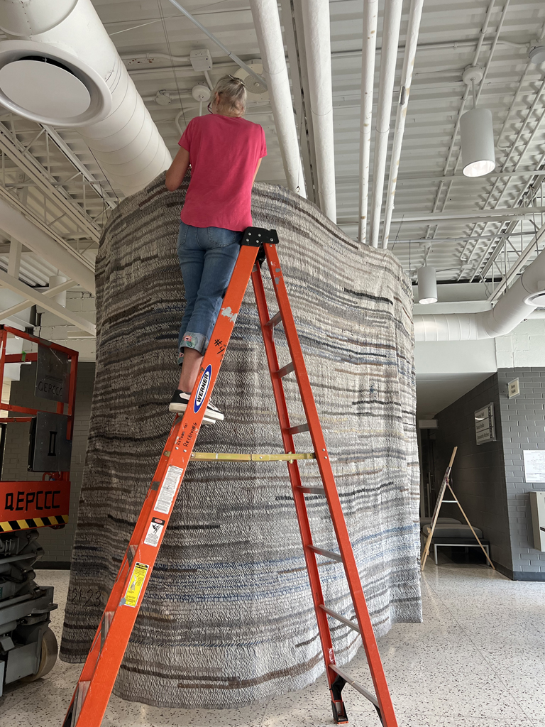 Festival installer: Caren installing the Time installation, World of Threads Festival 2023-24.