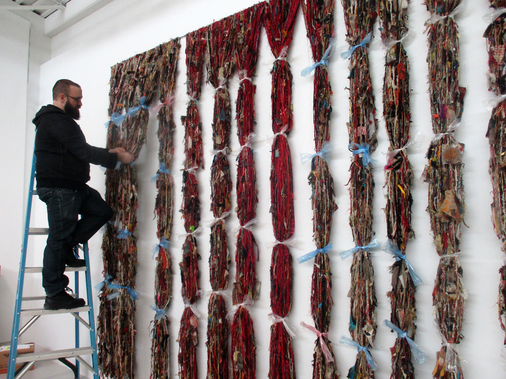 Festival Curator Gareth Bate tying up artwork prior to takedown.