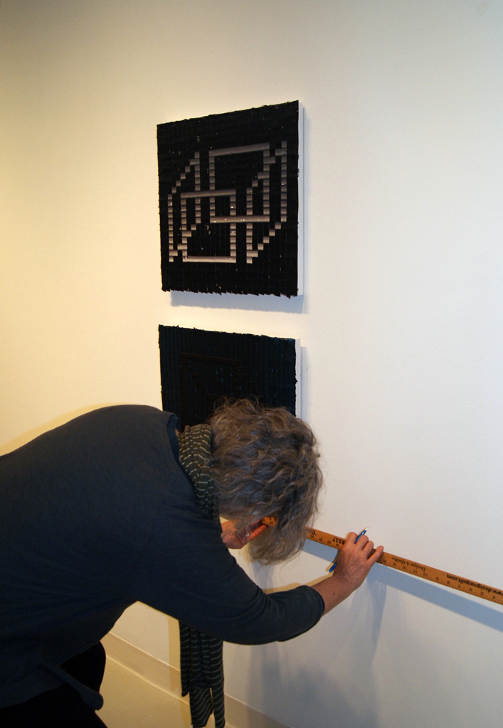 Festival installer: Carolyn, installing artwork for The Red and the Black exhibition, World of Threads Festival 2014.