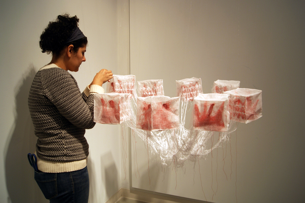 Artist: Ana Laura Diosdado, installing her artwork, The Red and the Black exhibition, World of Threads Festival 2014.