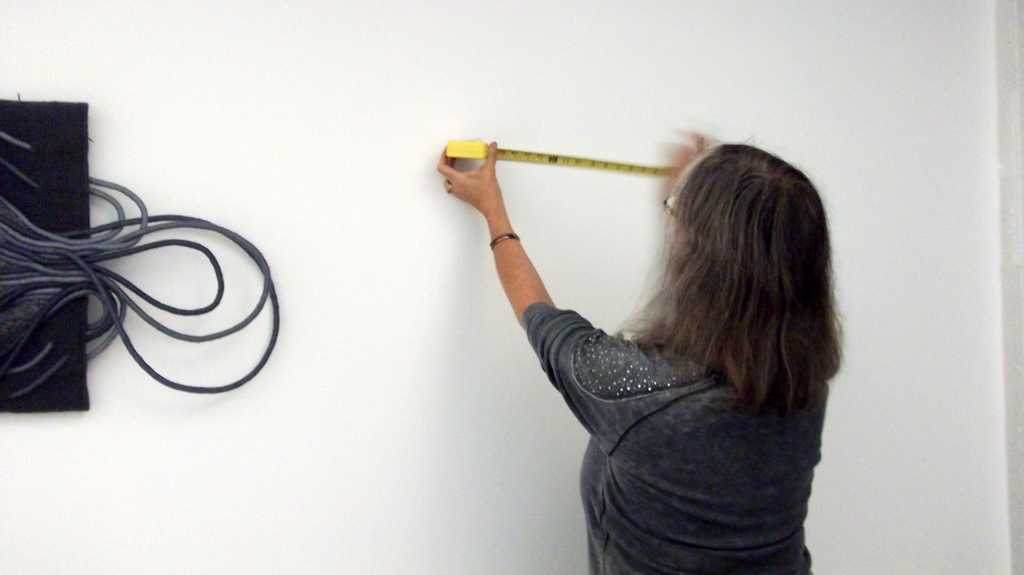 Festival installer: Ruth, installing artwork for The Red and the Black exhibition, World of Threads Festival 2014.
