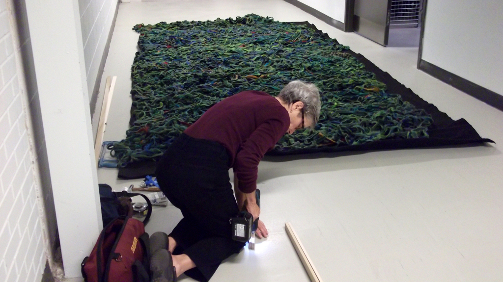 Artist: Mary Giehl installing her installation, World of Threads Festival 2014.